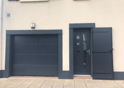 Porte de garage et porte d'entrée grises assorties.