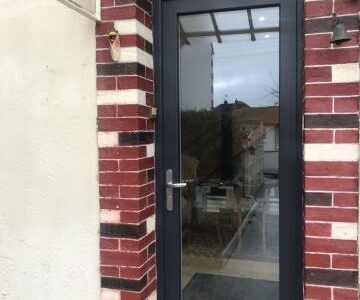 Porte d'entrée vitrée anthracite avec imposte.