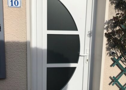 Porte d'entrée blanche avec hublot semi-circulaire.